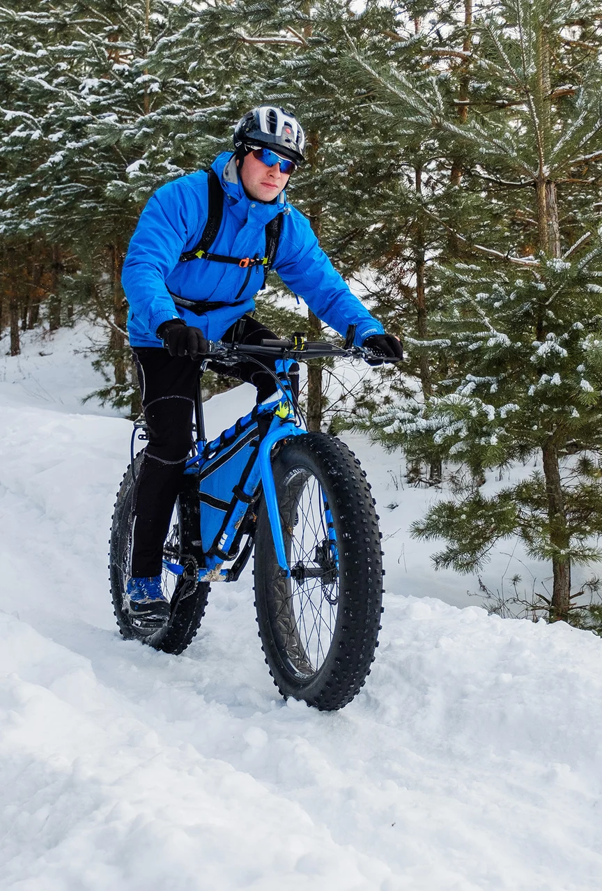 Man fat biking through forest.