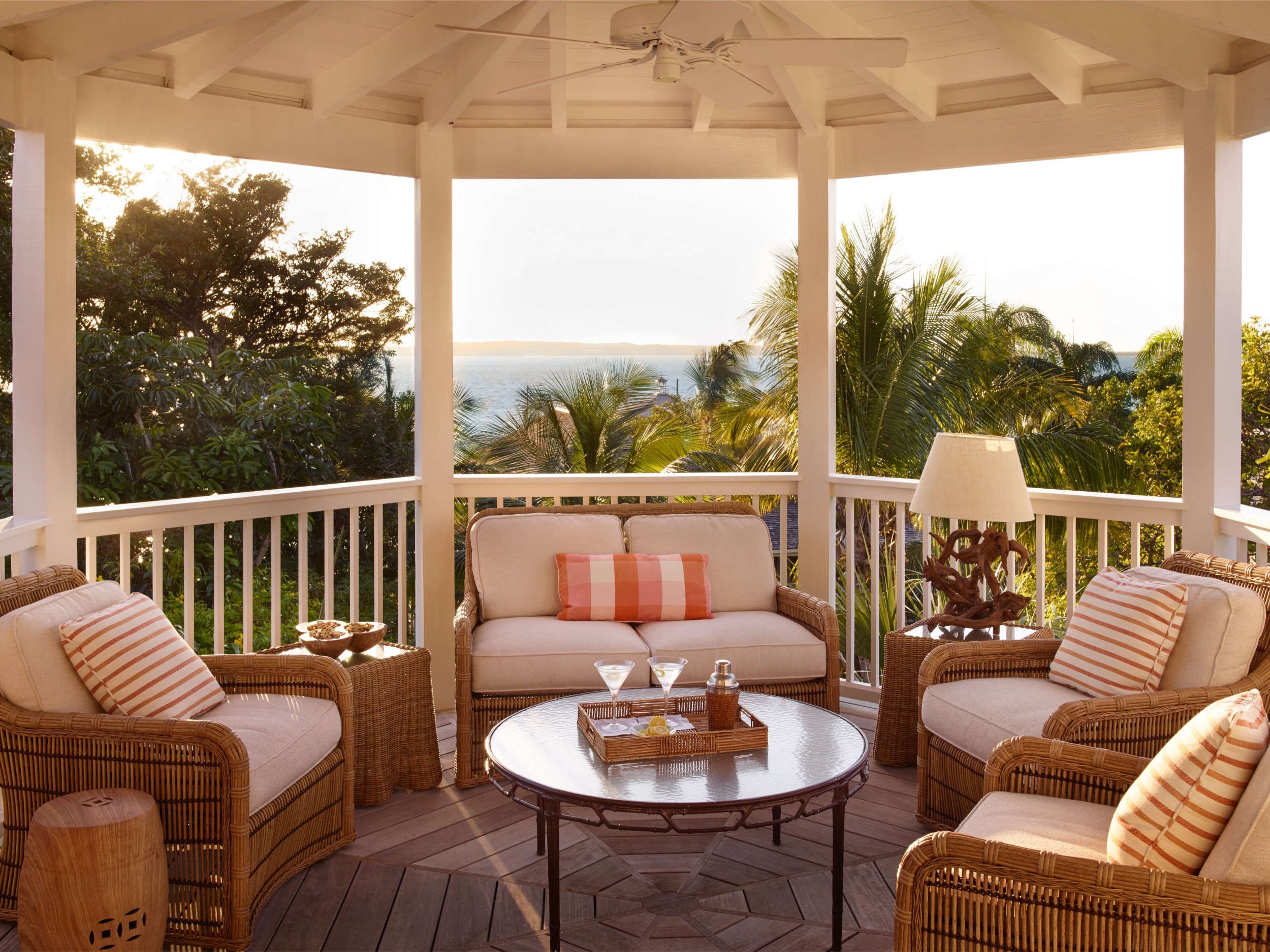 A veranda overlooks the ocean with martinis on the table during a summer evening.