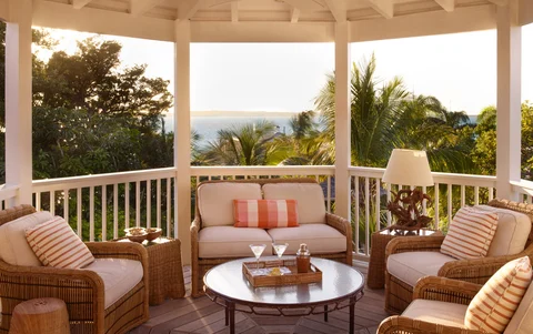 A veranda overlooks the ocean with martinis on the table during a summer evening.