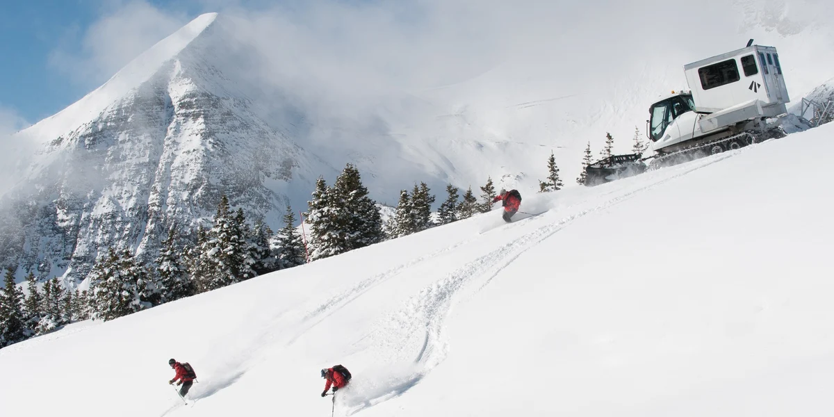 Skiers disembarking down a mountain from a catski,