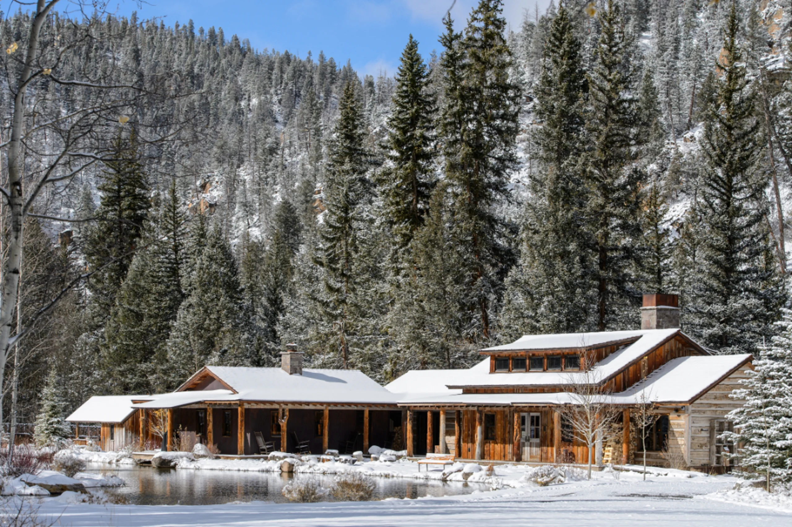 Exterior large log cabin covered in snow with snow covered trees behind in Taylor Canyon.