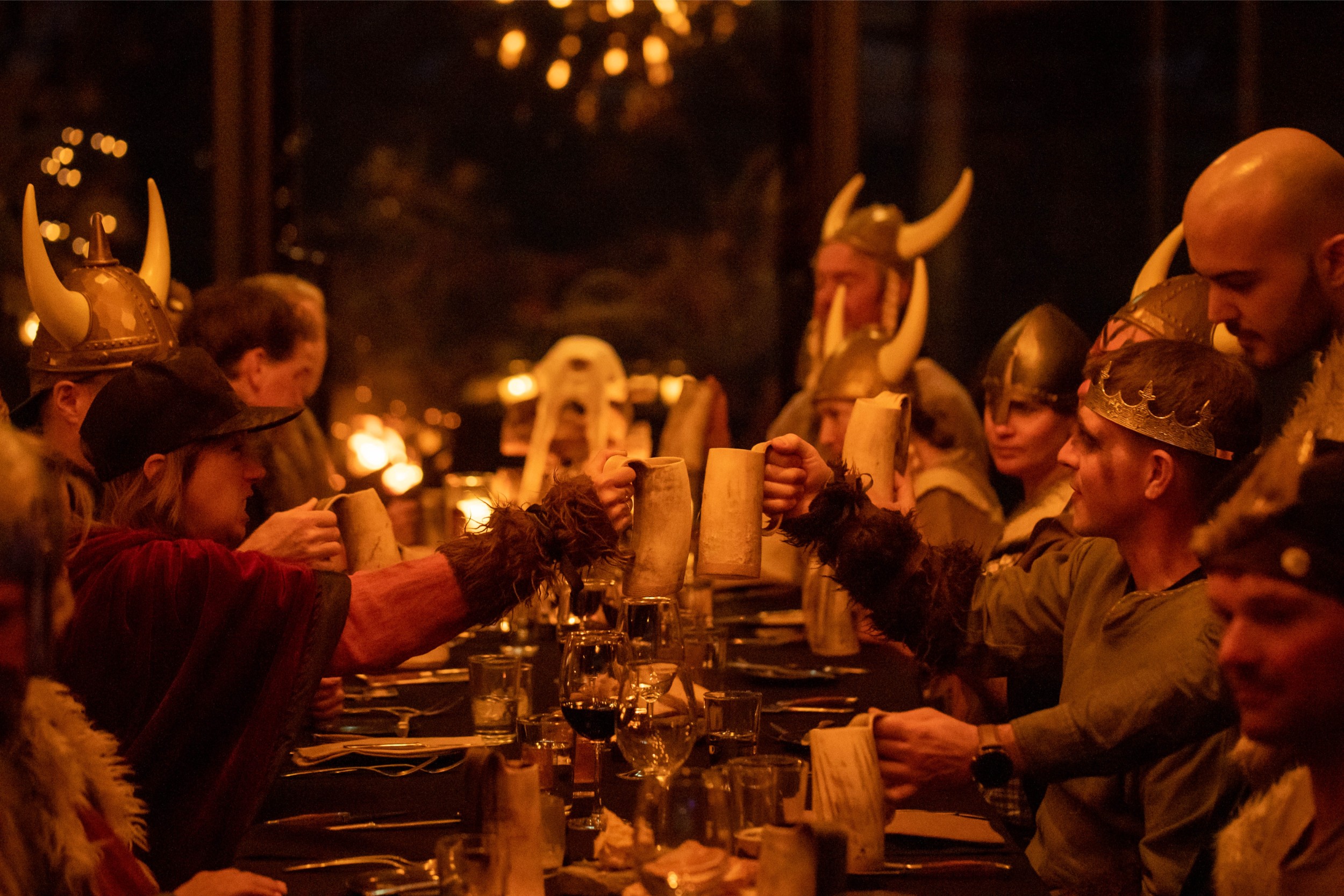 Large group of people enjoying a feast wearing horns and viking clothes.