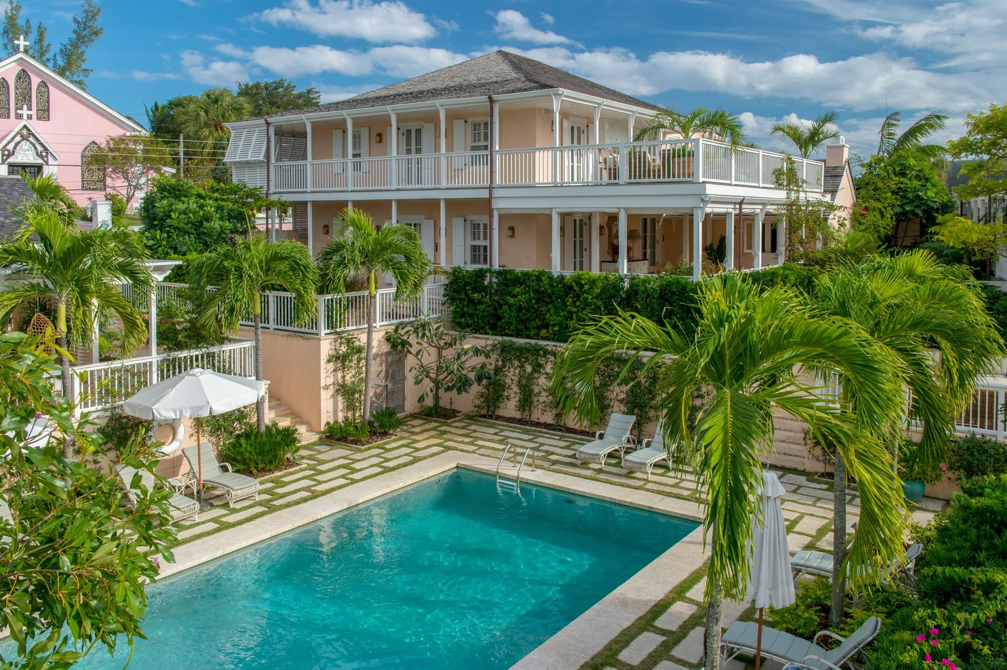 Exterior of pink and white lodge with a pool in the courtyard.