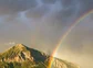 A vibrant rainbow passing in front of a lush green Colorado Mountain.