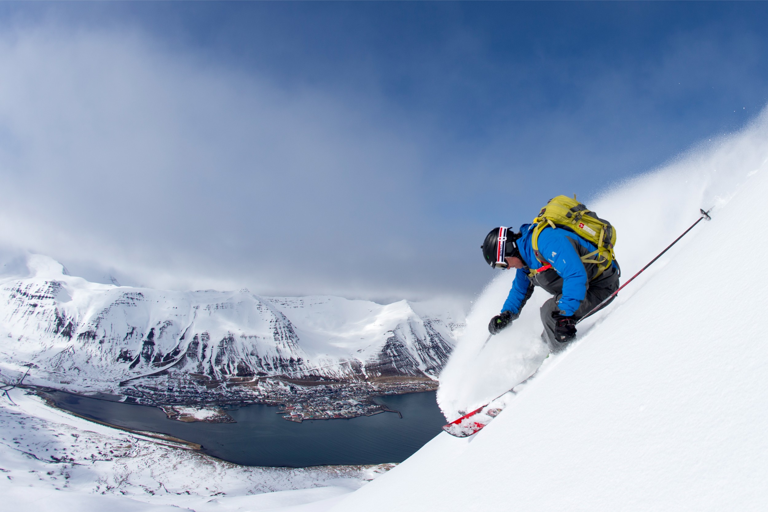 A person skiing downhill with a large lake in the background.