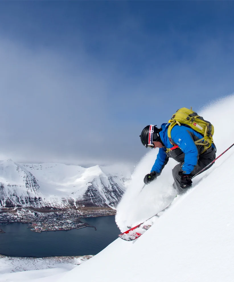 A person skiing downhill with a large lake in the background.