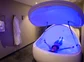 Person floating in an isolation tank with blue light.