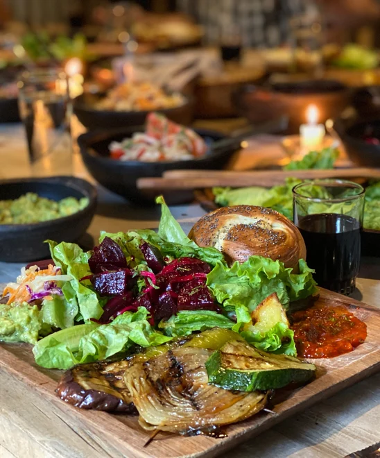 A large feast with fresh vegetables, guacamole, and bread.