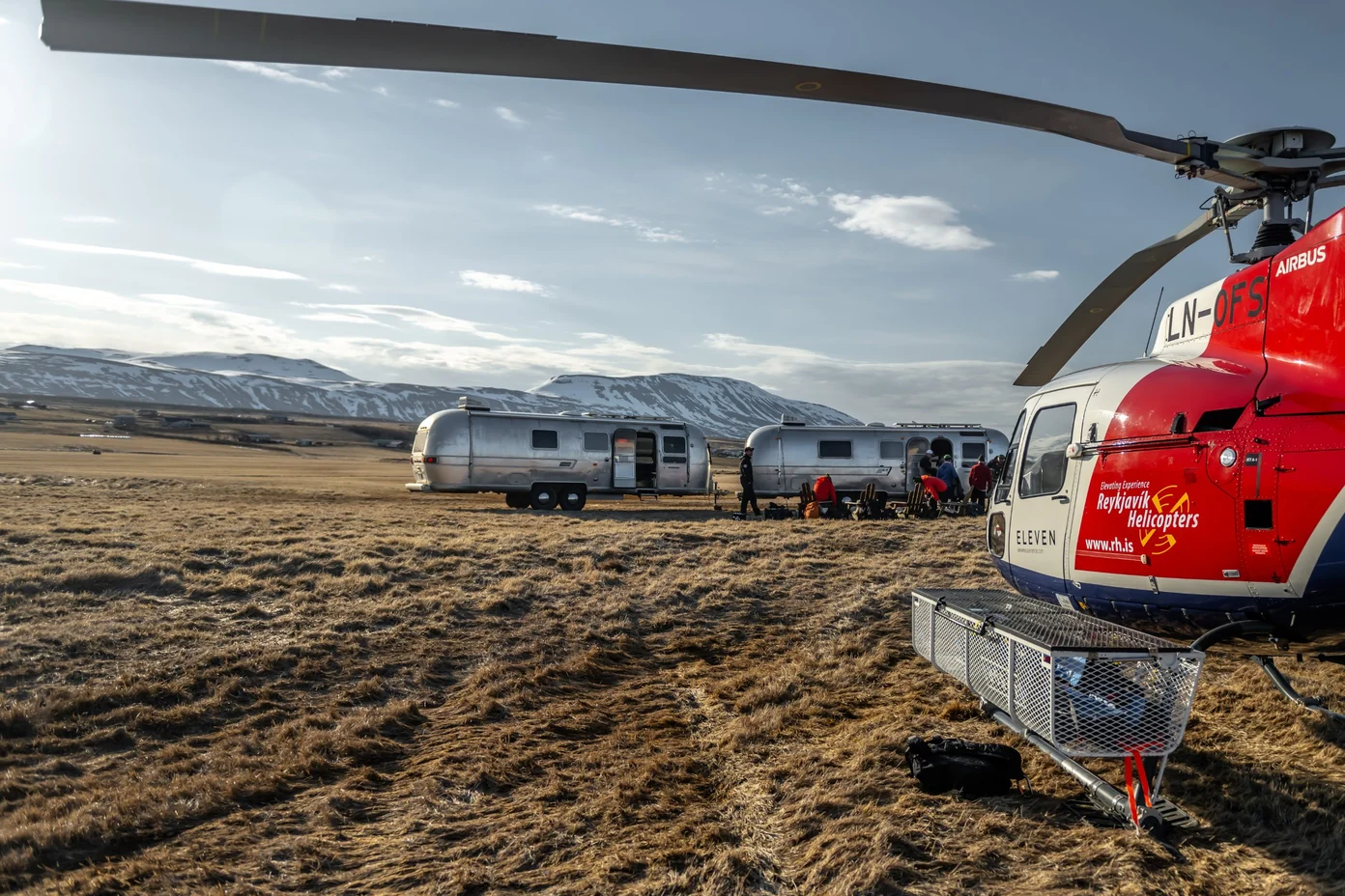 A helicopter parked next to Airstream campers in Iceland.