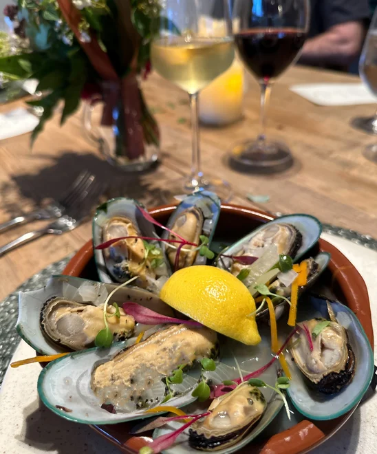A plate of mussels topped with a lemon wedge.