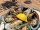 A plate of mussels topped with a lemon wedge.