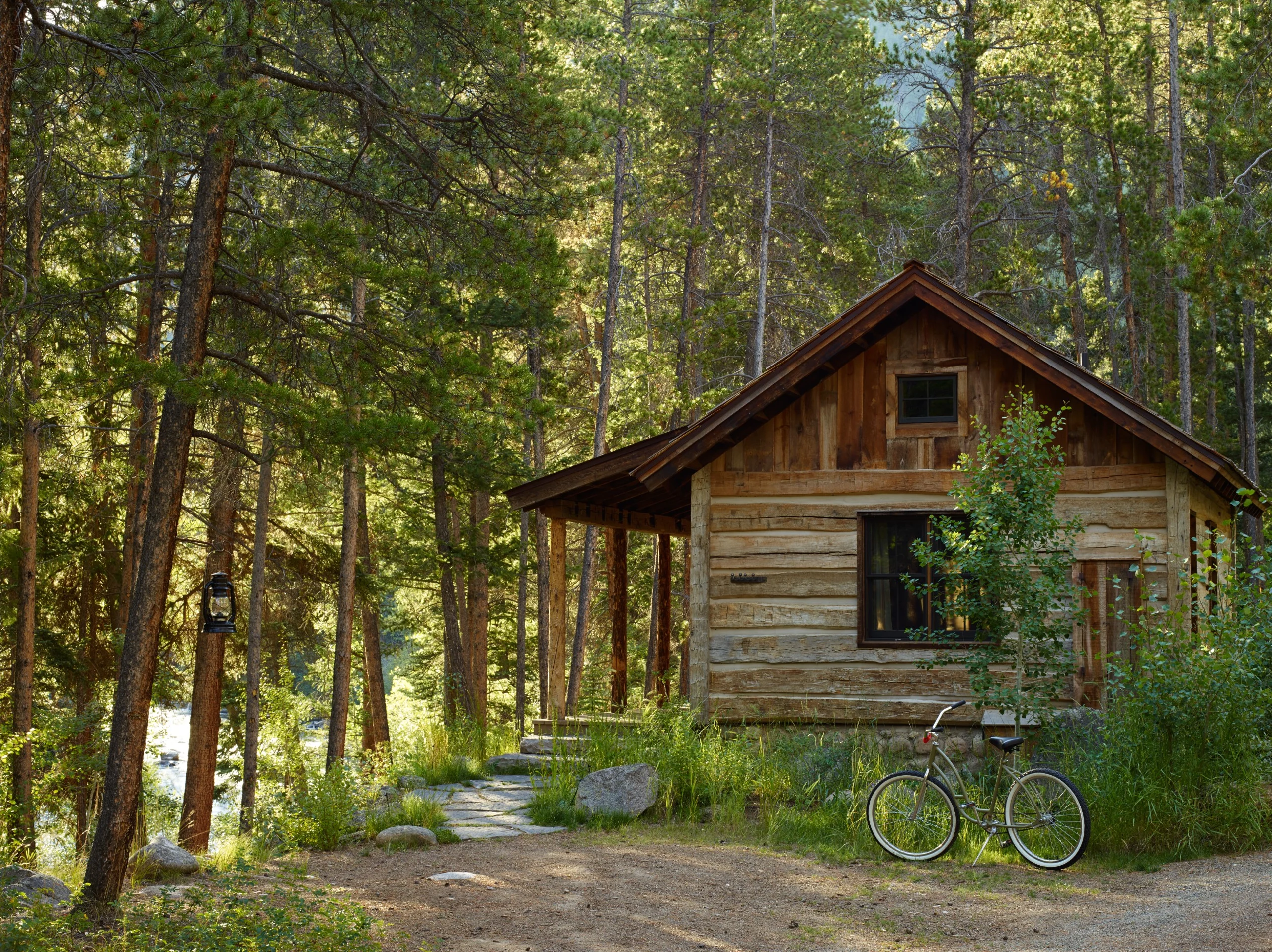 A bike parked outside of a wooden lodge in a heavily wooded area.
