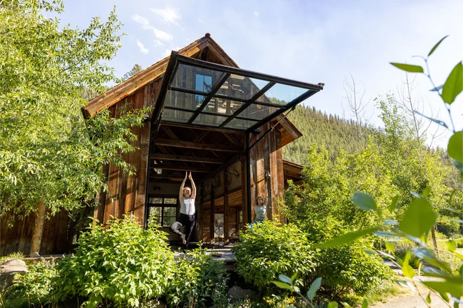 Two people doing yoga at an open garage door at lodge.
