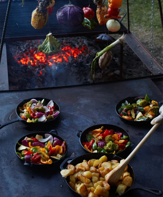 Vegetables and potatoes being on a large cast iron grill.