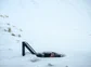 A person full submerged in a cold plunge, with snow fall.