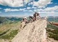 Climbers crawling across very thin and steep rocks along a mountain ridge.