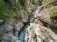 Hikers wearing helmets climbing through a watery gorge.