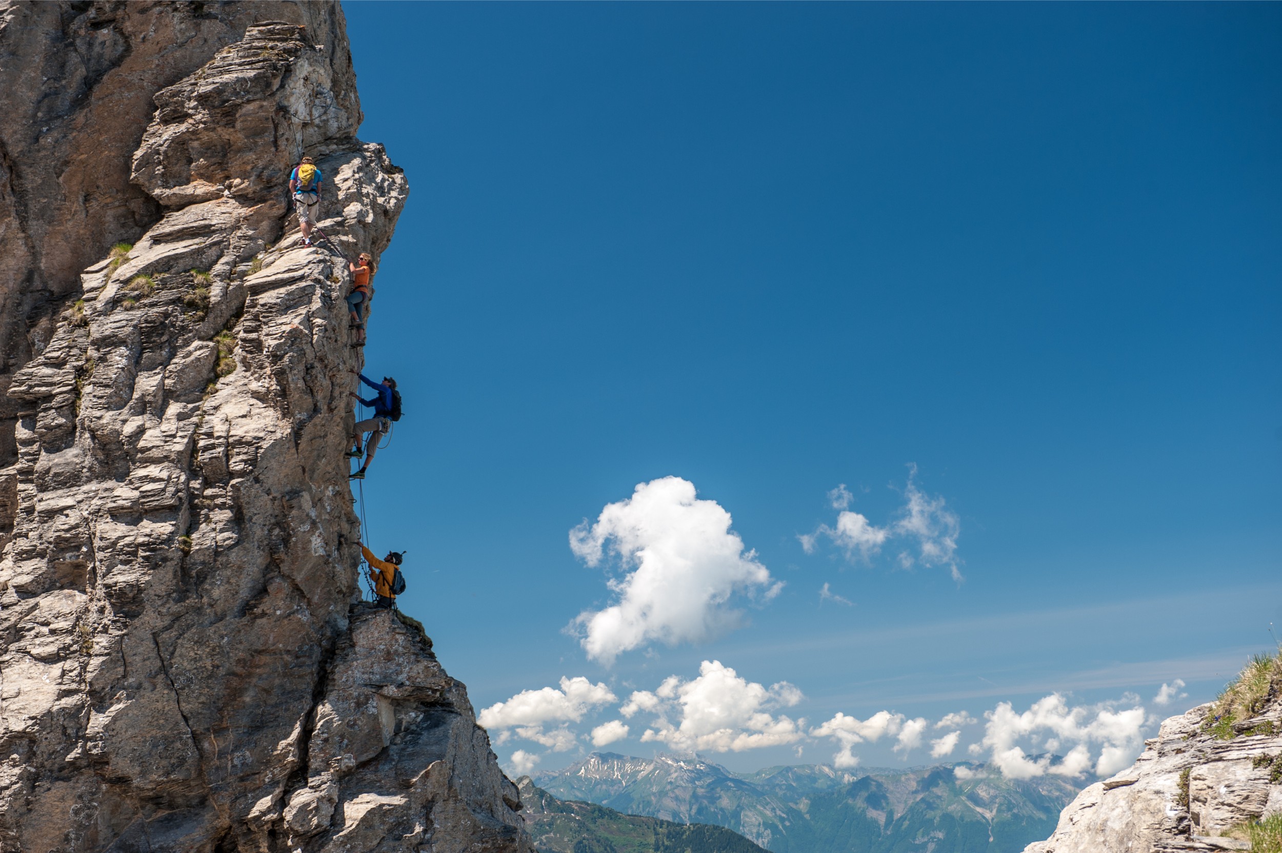 A group of people climbing up a vertical rock face in the alps.