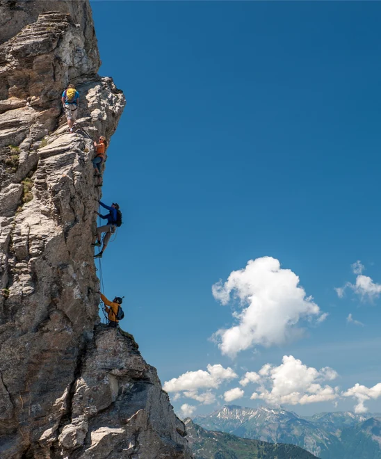 A group of people climbing up a vertical rock face in the alps.