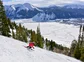 A skier going down a mountain with a view of a French town in the distance.