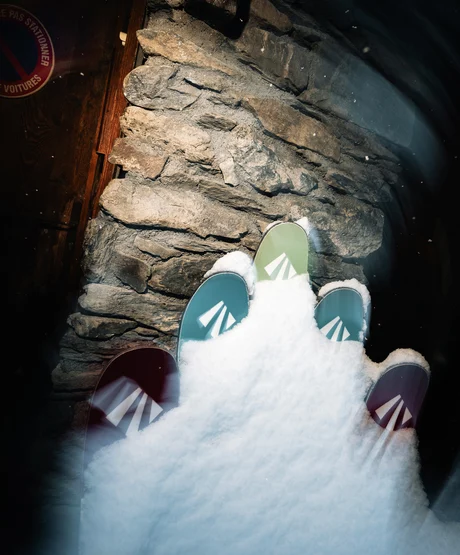 Several pairs of skis up against a lodge in the French Alps