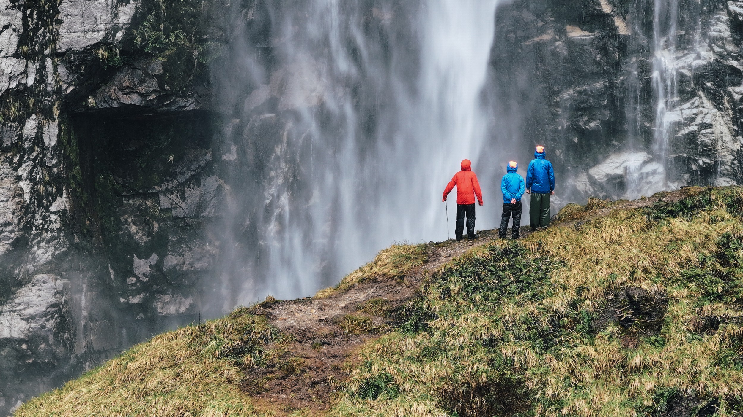 Three hikers enjoying the view of a large water fall in Chile.
