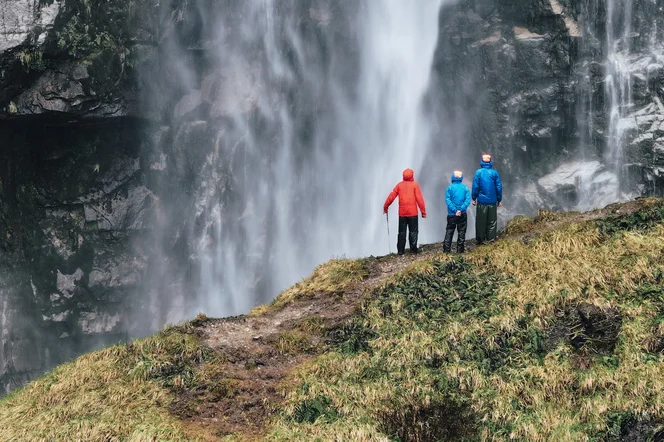 Three hikers enjoying the view of a large water fall in Chile.