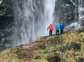 Three hikers enjoying the view of a large water fall in Chile.