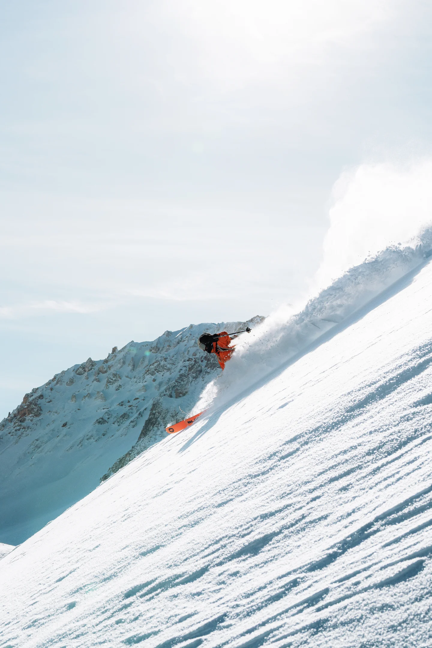 Person skiing down a mountain peak with a view of the summit in the background.