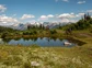 Two people mountain biking around a pond on a small mountain trail.