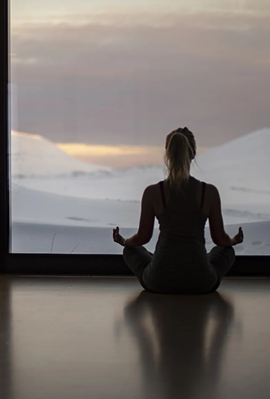 a person does yoga while looking out a window at the Icelandic landscape