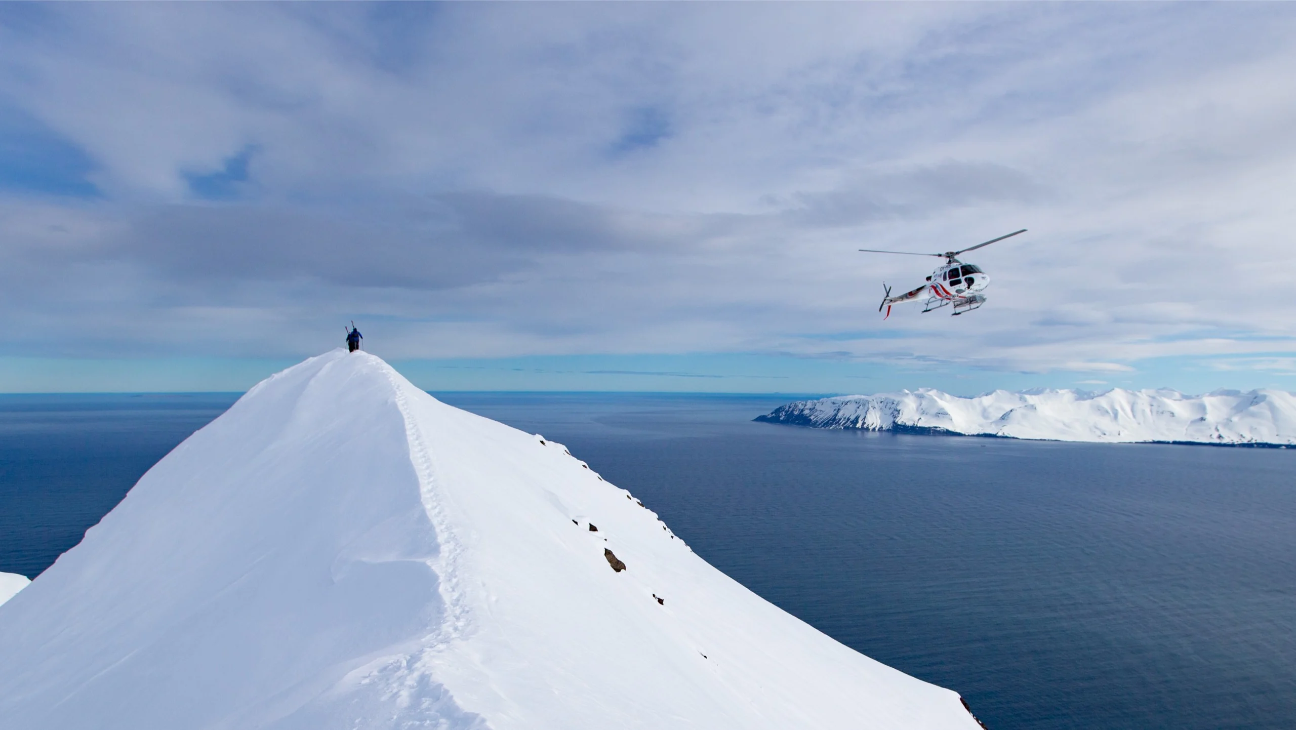 A skier being dropped off at the peak of a mountain at the oceans edge.