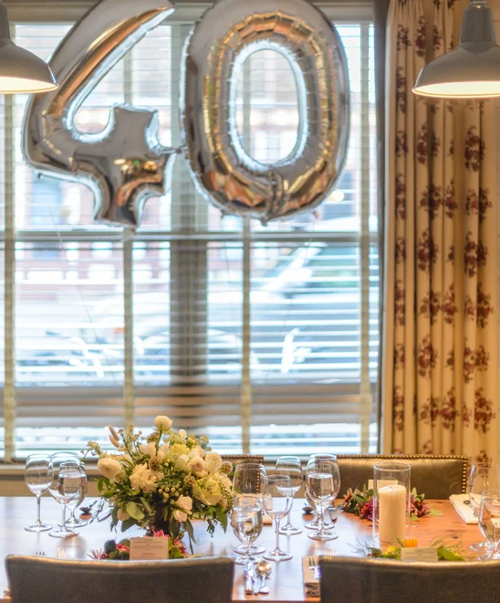 A birthday meal set up with a flower bouquet on the table and balloons.