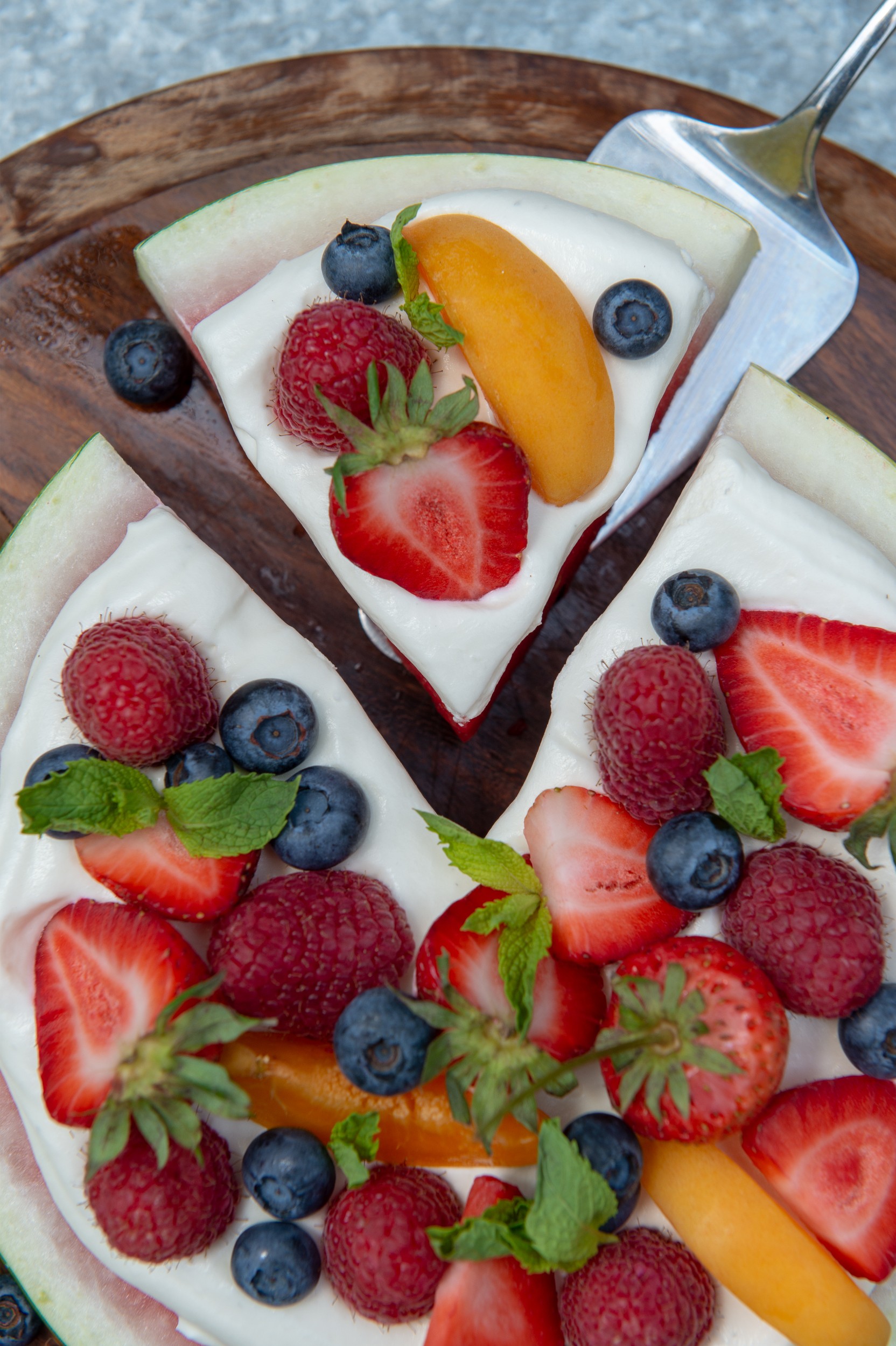 A slice of watermelon covered with cream and fresh berries.