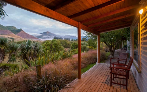 A summer evening is seen from the porch at Owen River Lodge. You can see the porch with chairs with a nice summer evening glow and greenery all around.