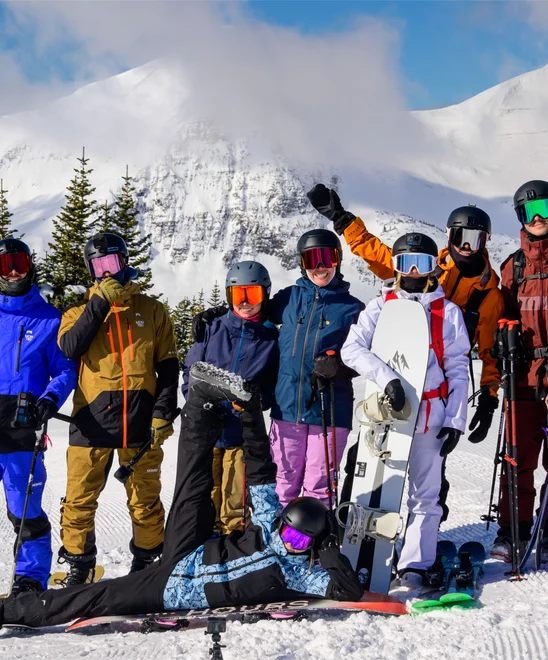 A group photo of skiers and snowboarders atop a mountain.