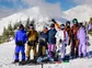 A group photo of skiers and snowboarders atop a mountain.