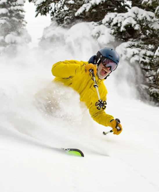 A person very happily carving while skiing in powdery snow.