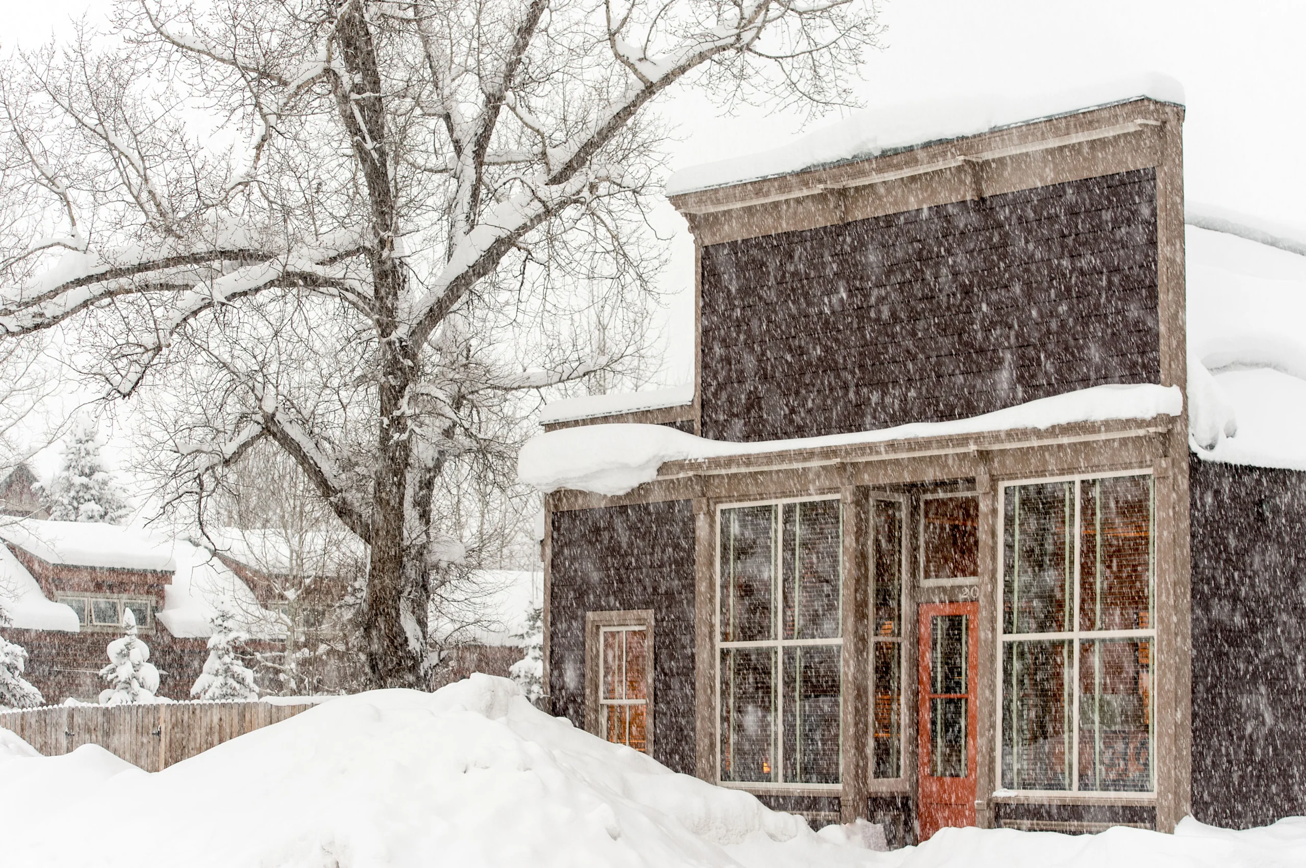 Exterior of a snow covered lodge, the building is a historic western building and there is snow in the foreground.