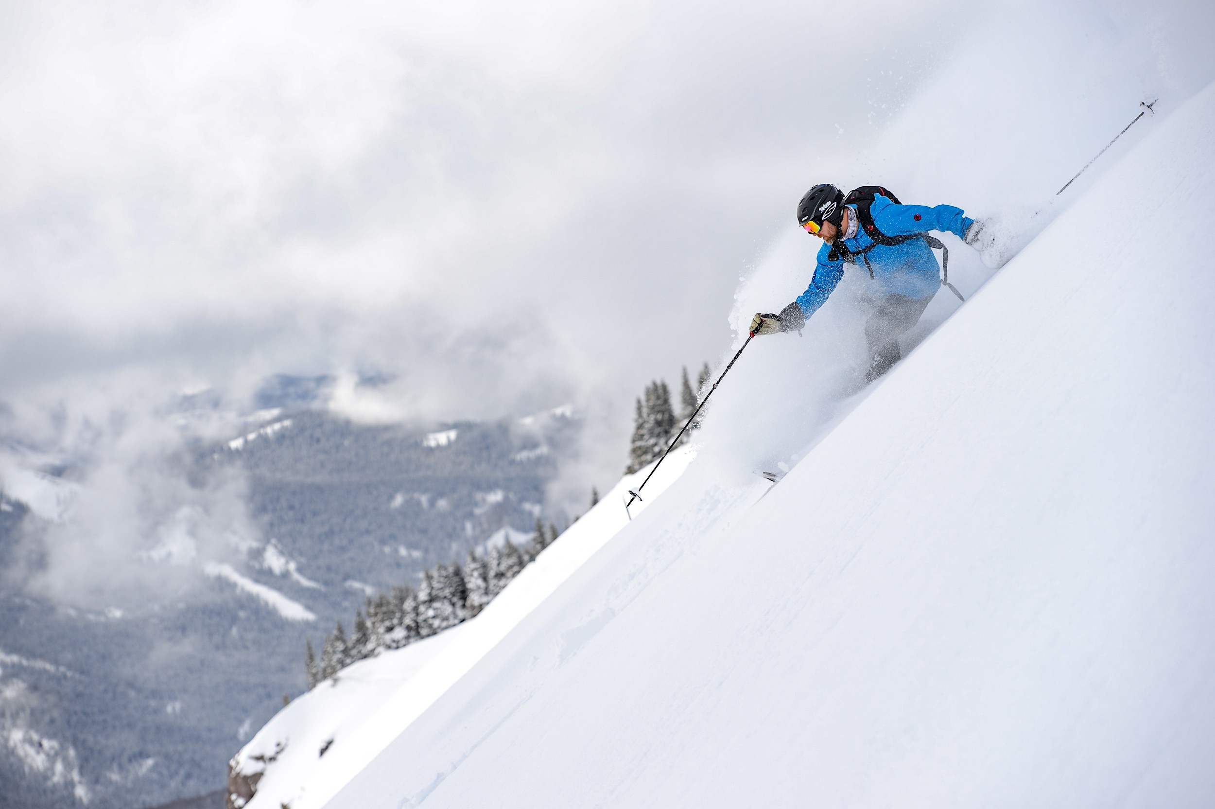 A man surrounded by snow powder skiing down a mountain in Colorado.