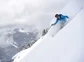 A man surrounded by snow powder skiing down a mountain in Colorado.