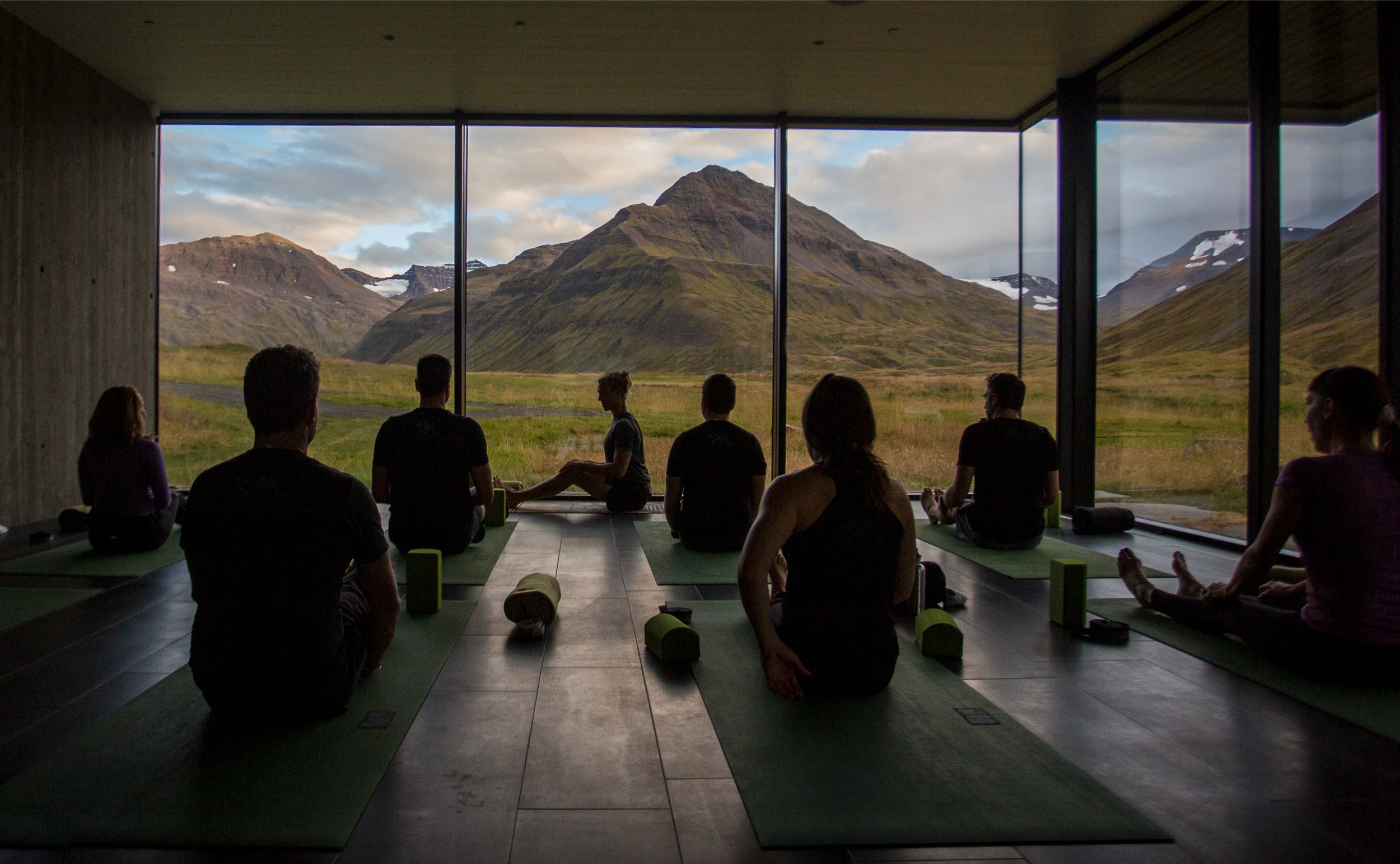 Group of people in a yoga class with a view of mountains.