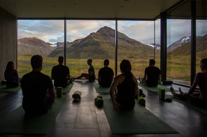 Group of people in a yoga class with a view of mountains.