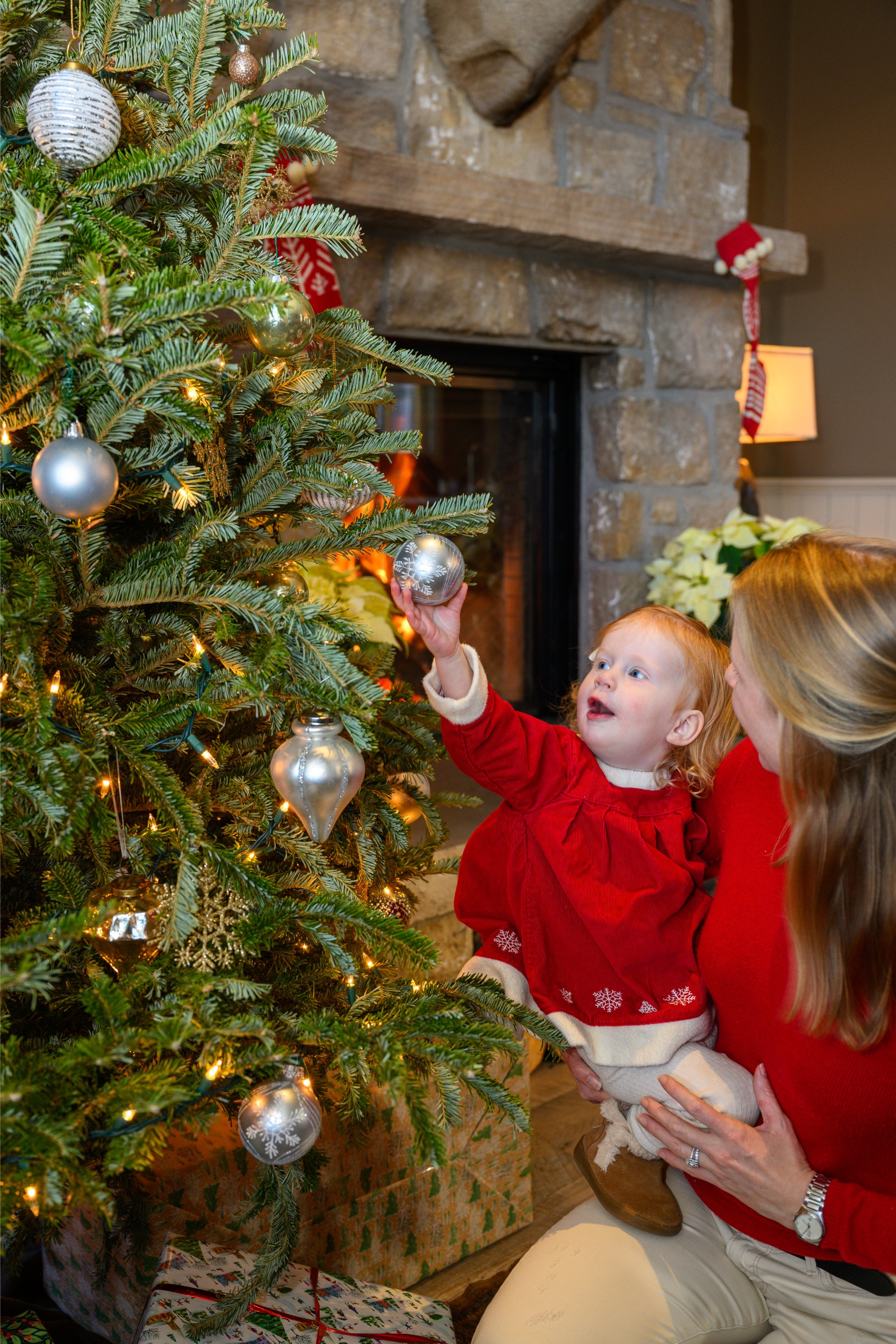 A mom holding her child looking at a Christmas tree ornament.