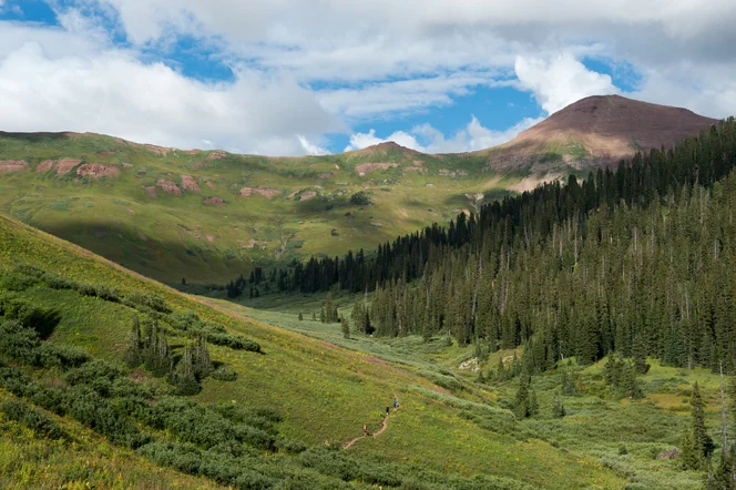 A hiking trail between Aspen and Crested Butte through a lush green valley.