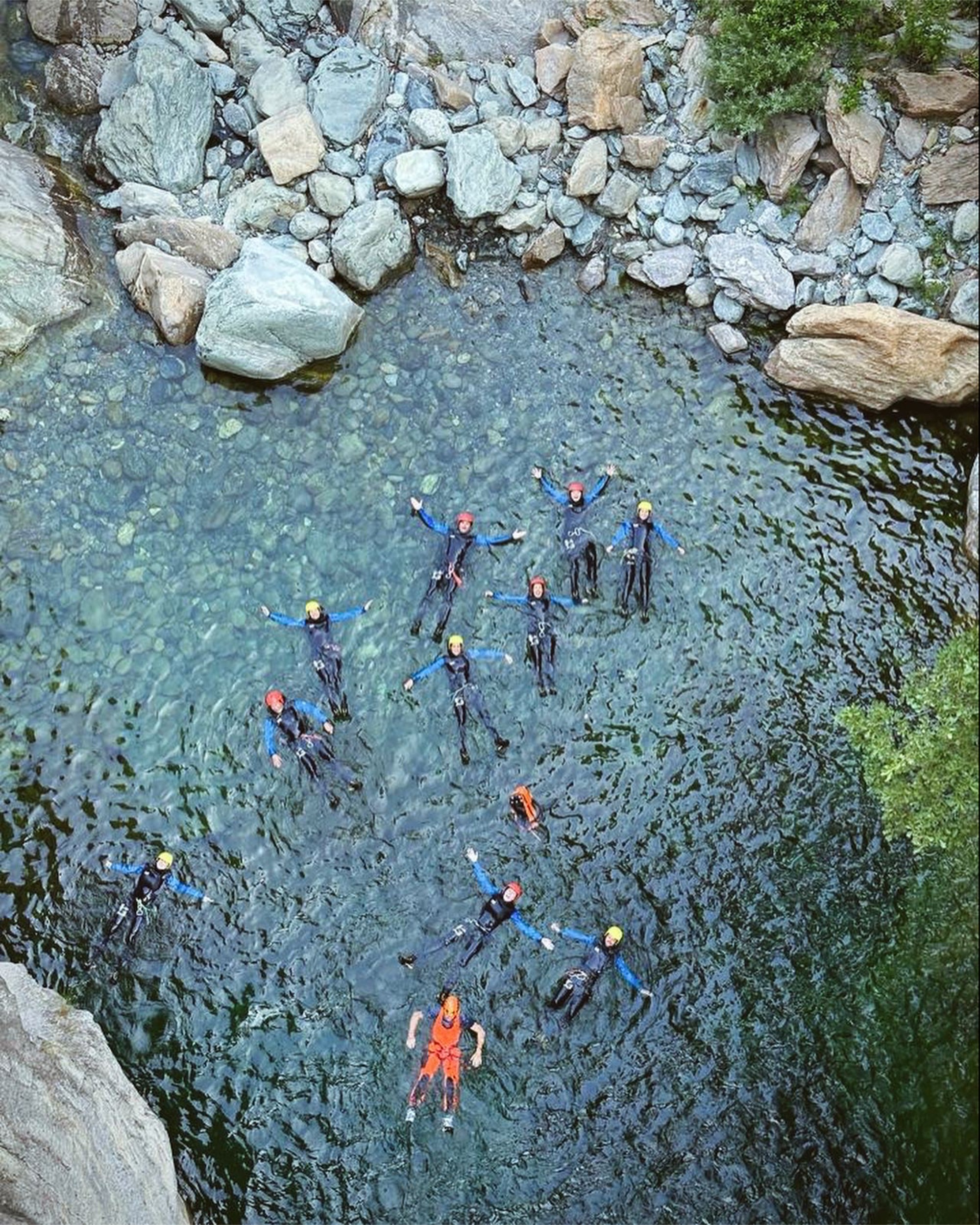 A group of climbers floating on their backs in a small mountain pond.