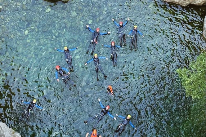 A group of climbers floating on their backs in a small mountain pond.