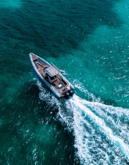 A scorpion rib boat has a wake as it sails through turqouise waters.