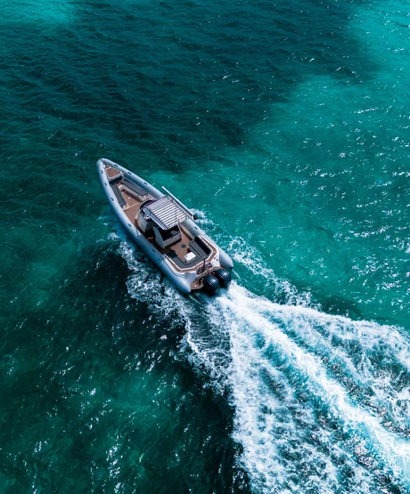 A scorpion rib boat has a wake as it sails through turqouise waters.