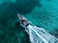 A scorpion rib boat has a wake as it sails through turqouise waters.